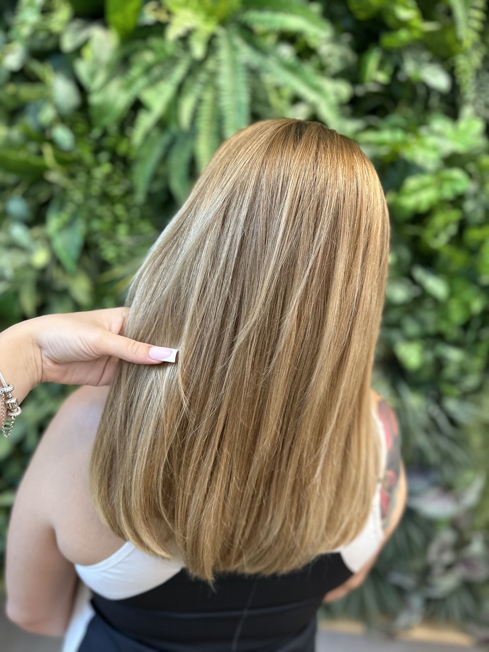 Airtouch se střihem: polodlouhé rovné vlasy ve zlaté blond, ruka držící pramen (Antonie)