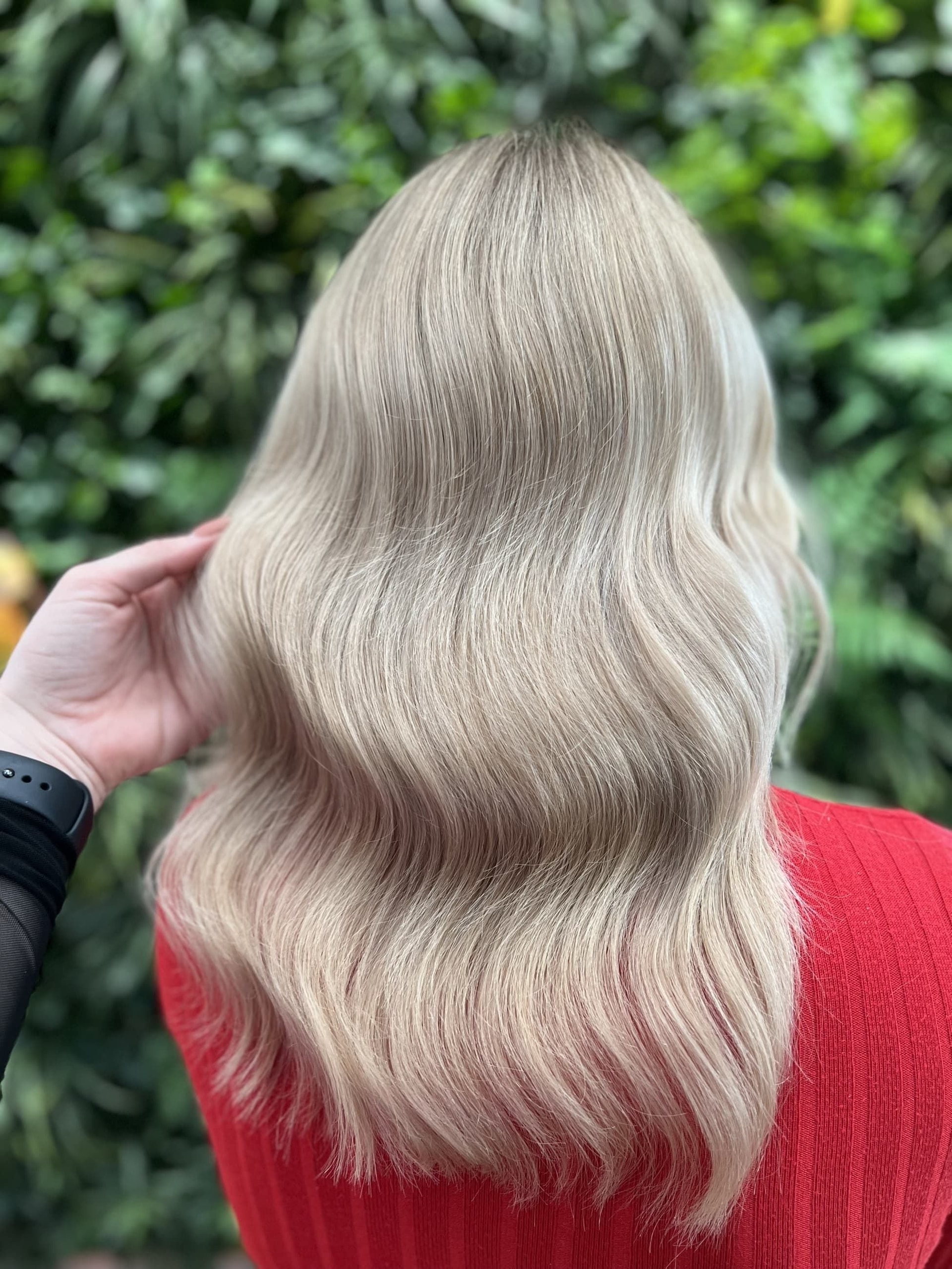 Airtouch: vlasy po ramena s měkkými vlnami v mléčně blond, tmavší kořínek, v pozadí zeleň