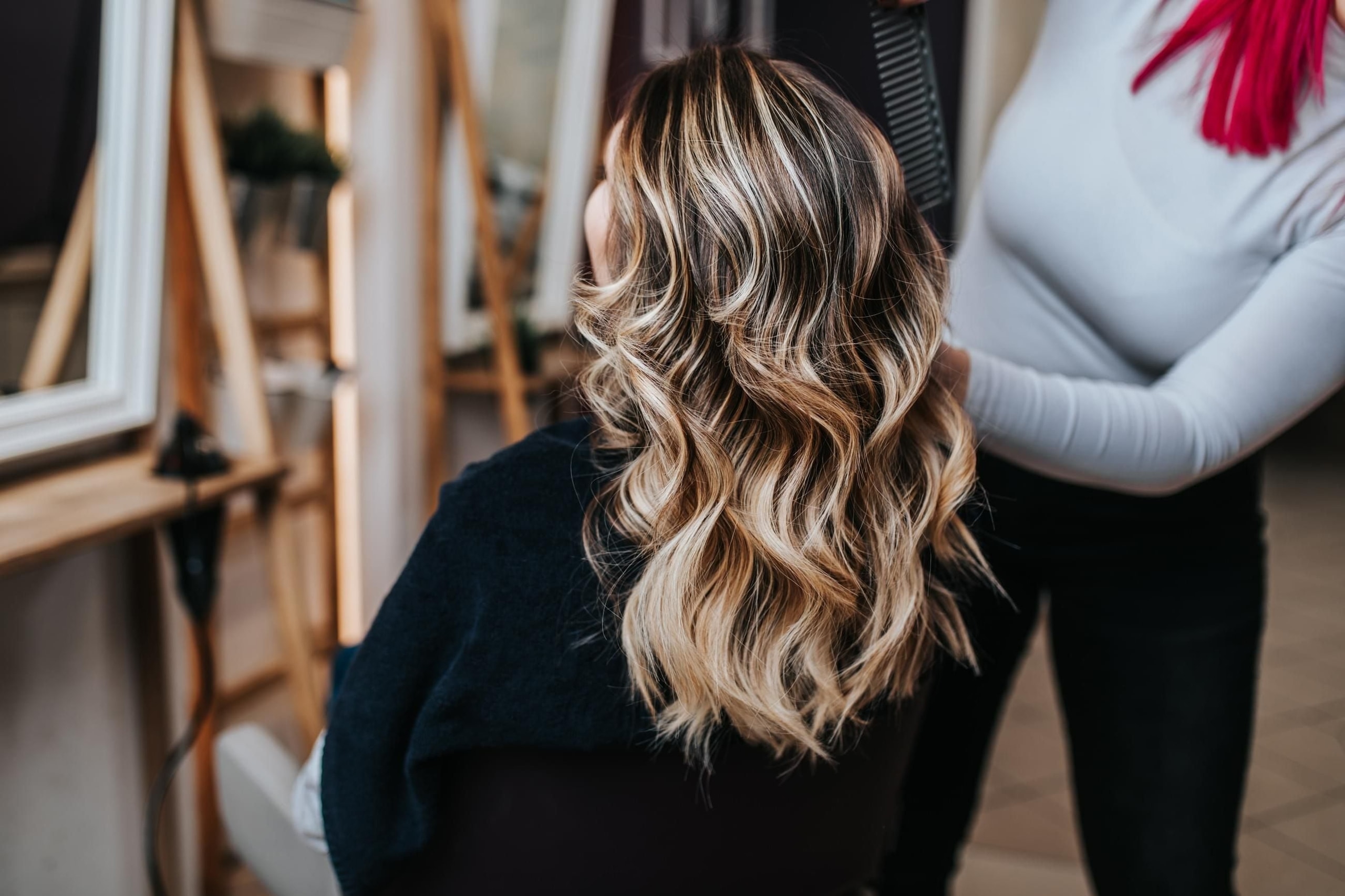 Balayage: dlouhé vlnité vlasy s tmavými kořínky a světlými medovými prameny v délkách, v salonu