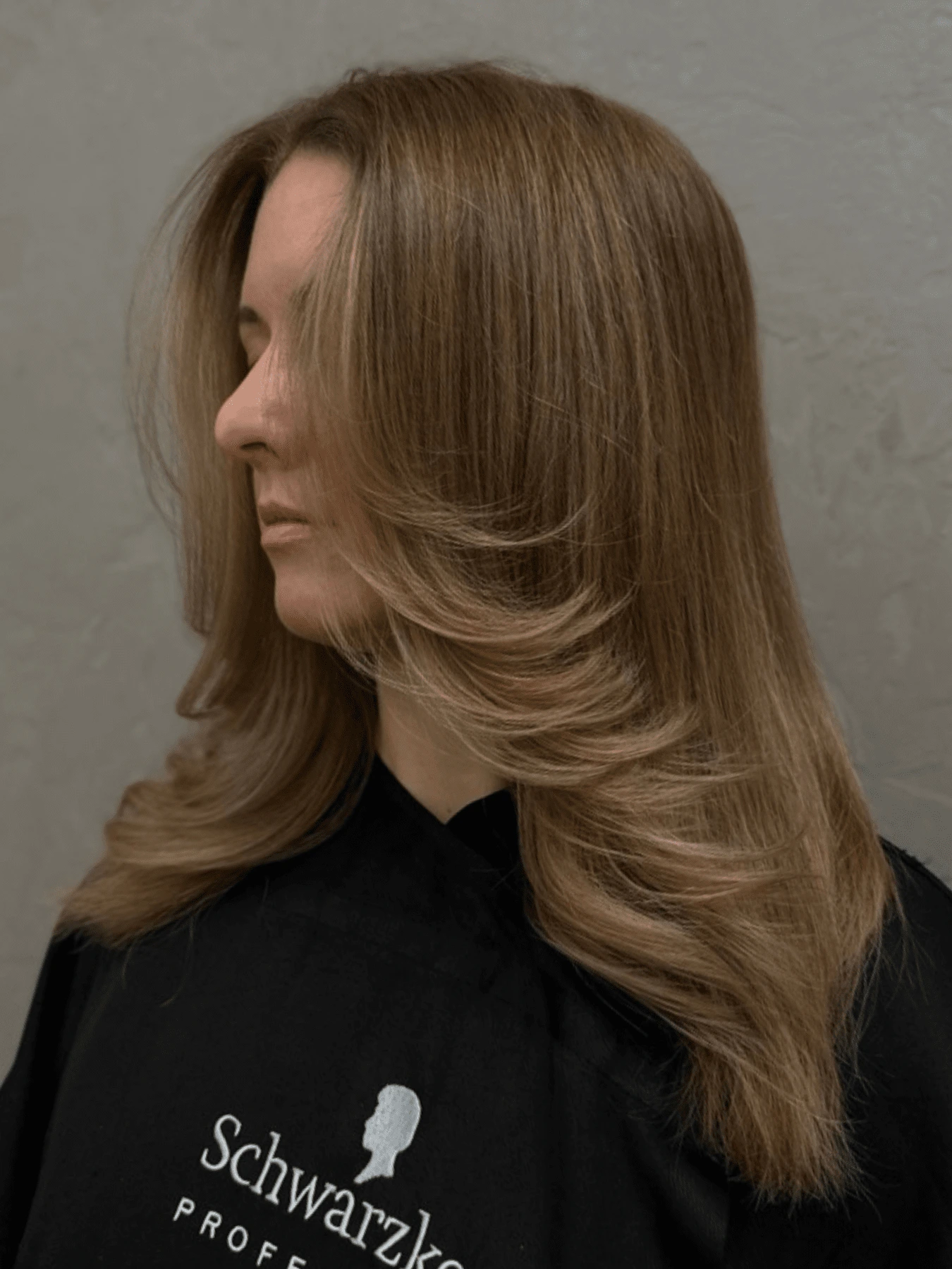 Butterfly cut: dlouhé hladké vlasy v teplé hnědé s medovými odlesky, prodloužené vrstvy vyfoukané od obličeje