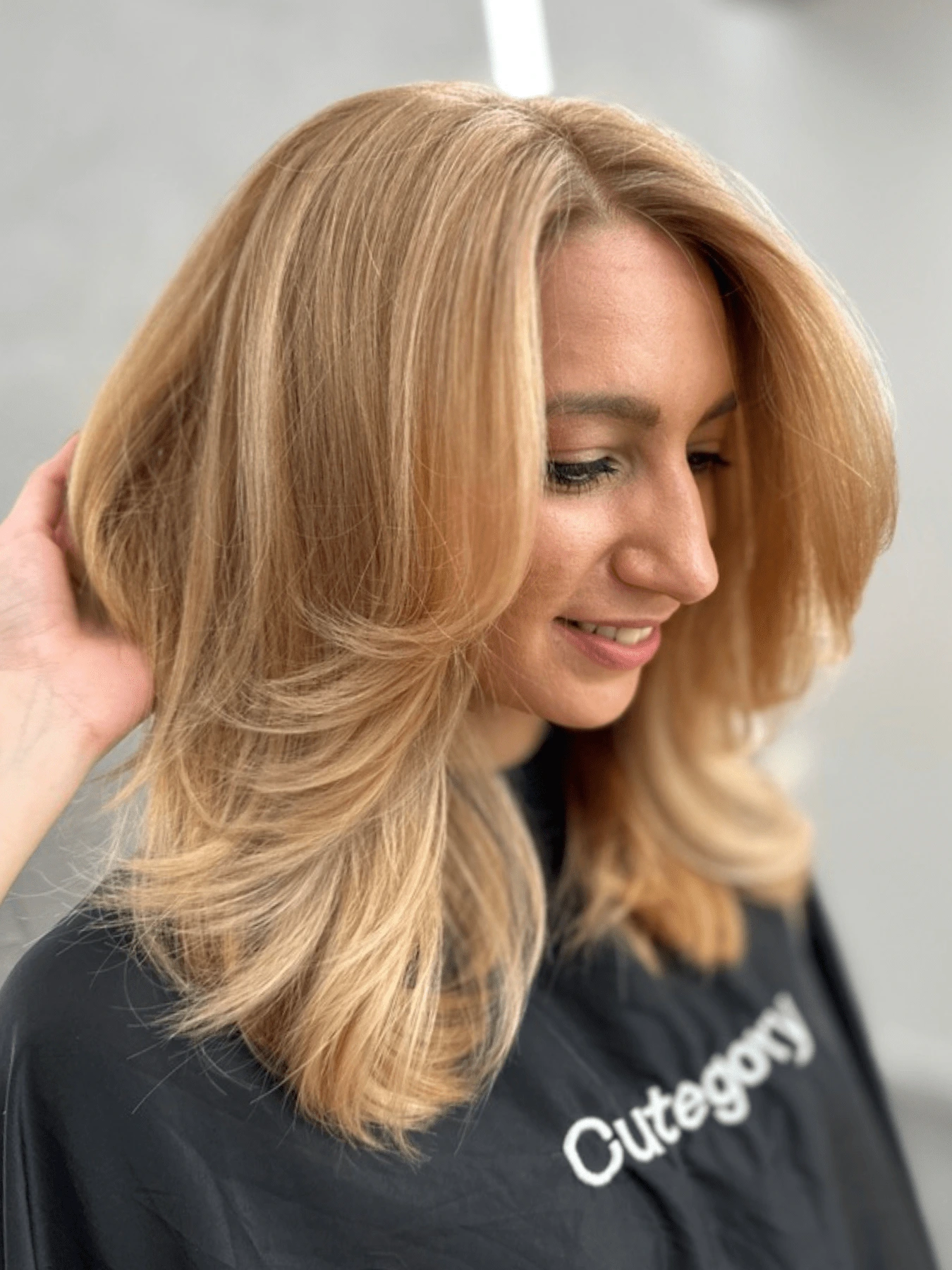 Butterfly cut: vlasy po ramena, měděná blond se světlejšími prameny, vrstvy kolem obličeje vyfoukané ven