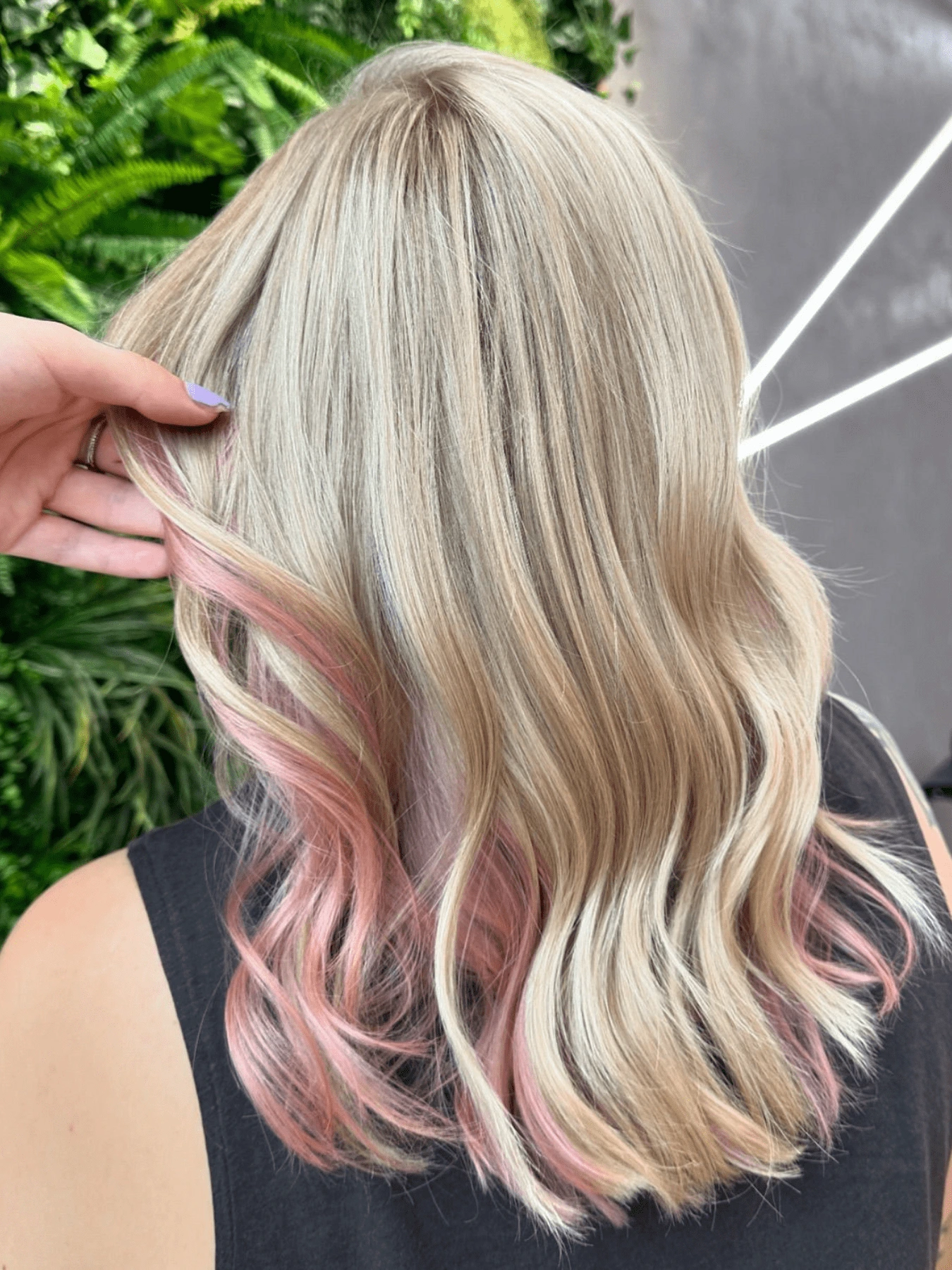Kreativní barvení: vlnité blond vlasy pod ramena s růžovými prameny vespod, vlasy drží ruka (Klára Valnerová)
