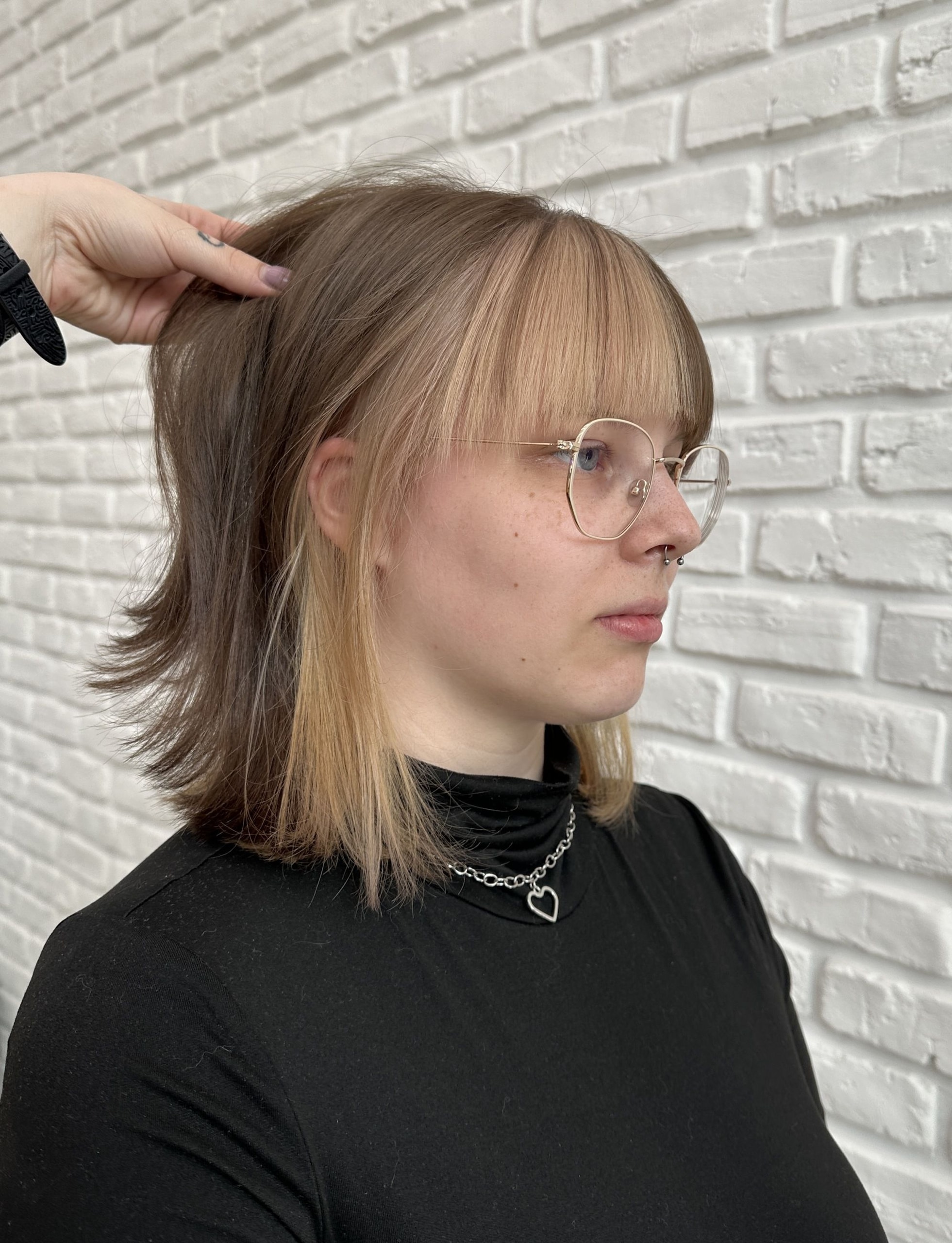 Kreativní barvení: vrstvené vlasy s ofinou a výrazně světlým podbarvením spodní části, bílá cihlová zeď (Klára Valnerová)
