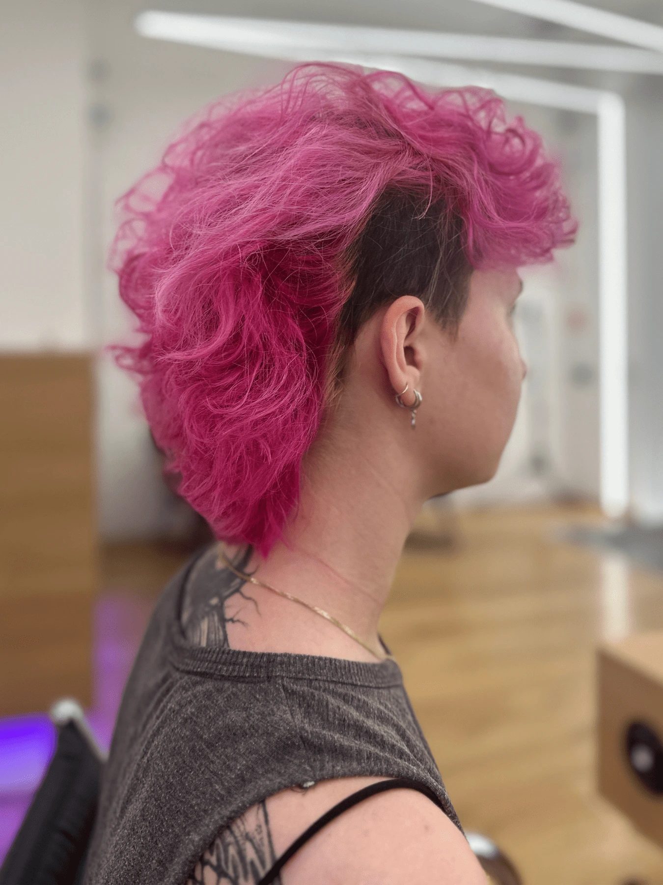 Mullet: sytě růžové vlnité vlasy, objemné nahoře a vzadu, tmavé krátké boky