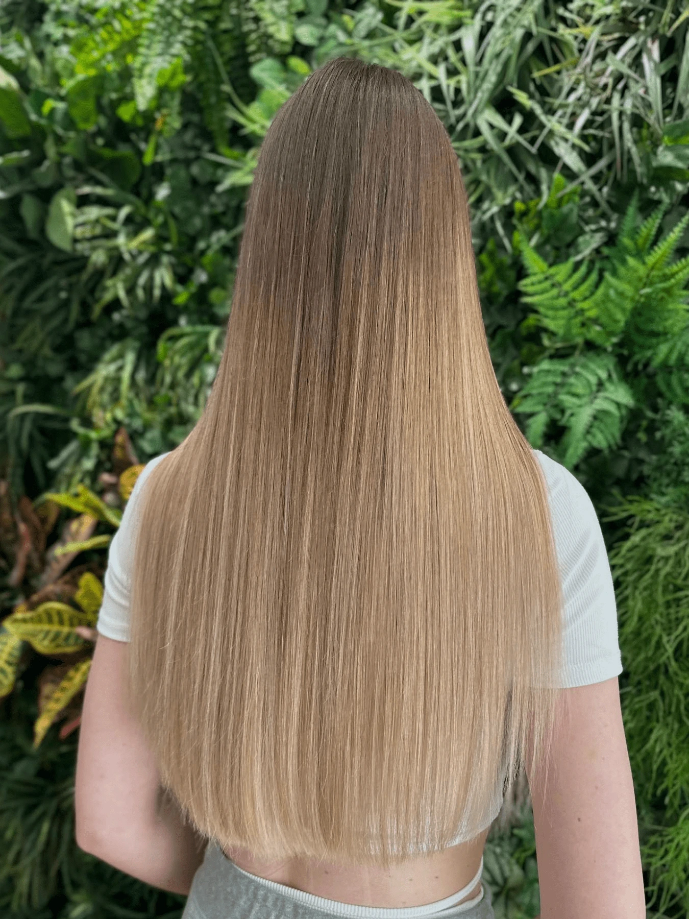 Střih vlasů: dlouhé rovné vlasy s plynulým přechodem z tmavšího blond u kořínků do světlého blond, hladké konce